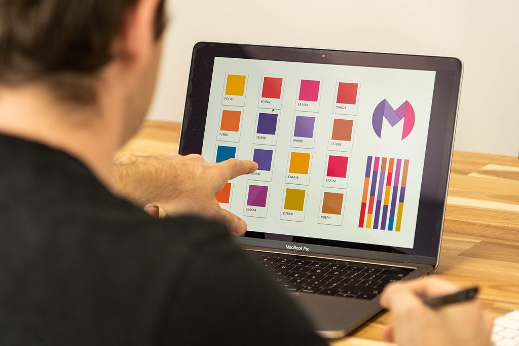 a person pointing to a laptop screen showing colour palette selection for logo design