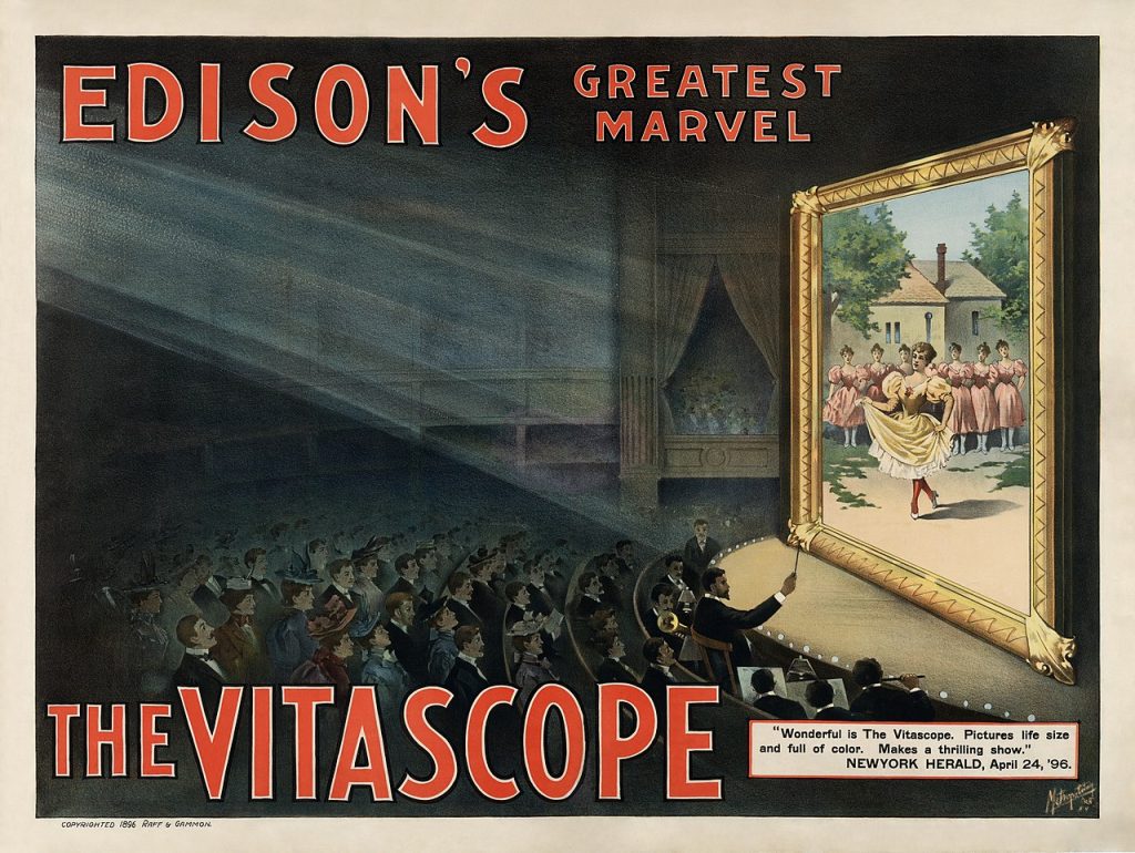 Poster for The Vitascope showing a movie audience, watching a large screen with women dancing on it. A small orchestra plays in front of the screen. The theatre has a box which several more people have packed into. circa 1896