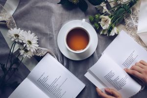 Woman reading a book with tea and flowers