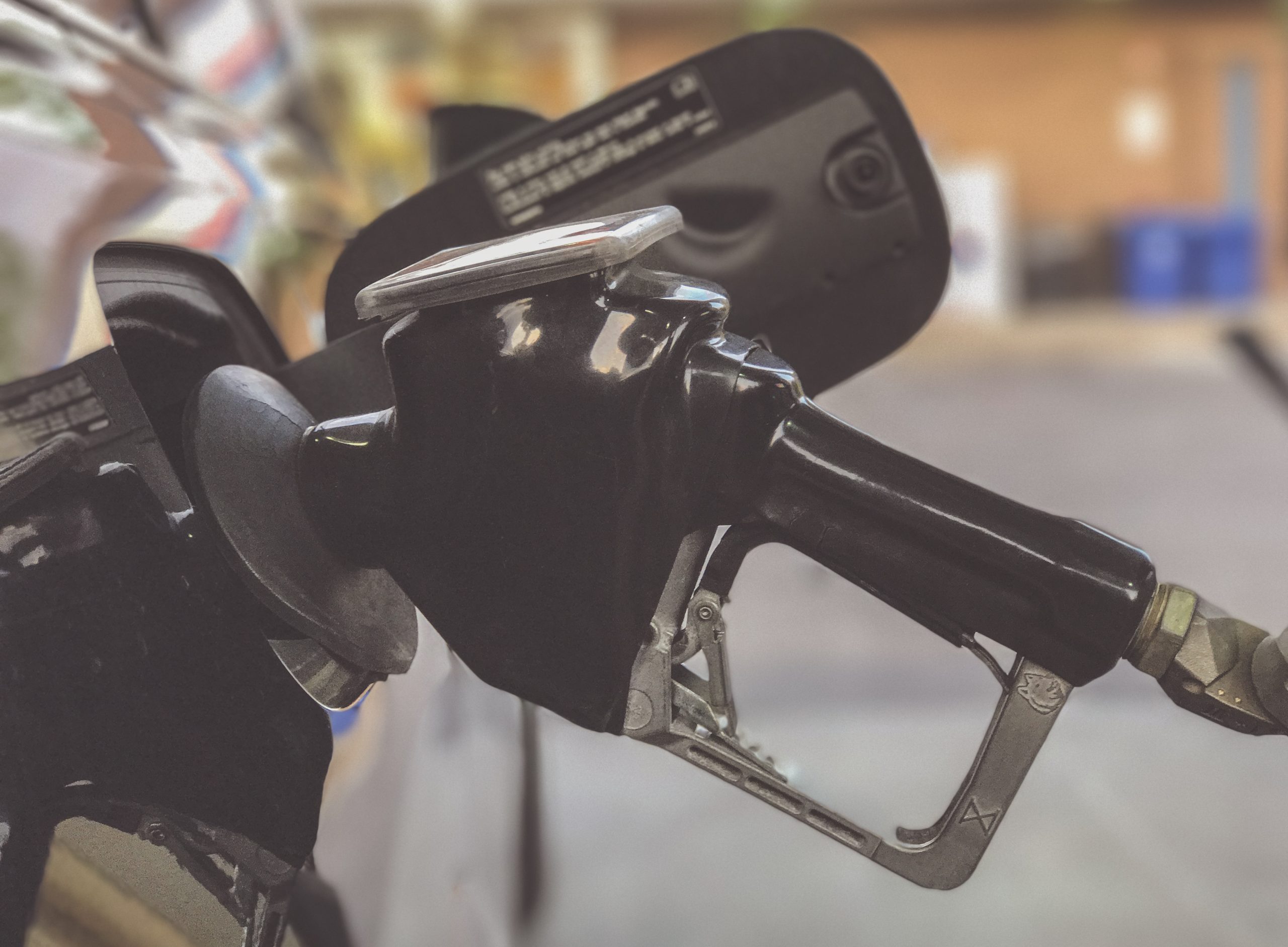 Photo of gasoline pump handle inserted into a car.