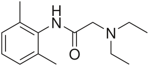 Line-bond structure of lidocaine, C14H22N2O. An amide is flanked by two relatively large and complicated groups. One is a benzene ring with 2 methyl substituents. The other is a tertiary amine group with 5 total carbons.