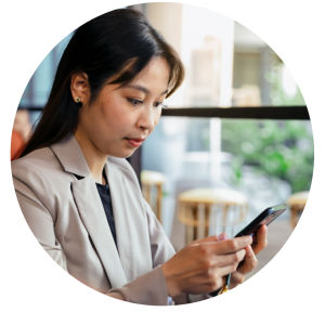 Linh, a woman in her twenties, is sitting in a cafe looking at her mobile phone. She is wearing a beige blazer and black top.