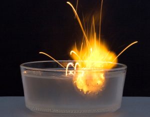 Sodium igniting in a bowl of water, bursting into flames.