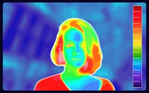 Photo of lady through IR camera. Warmer areas are present in a red colour against the darker blue background.