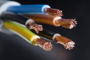 Copper wires in different coloured plastic coatings on a black background.