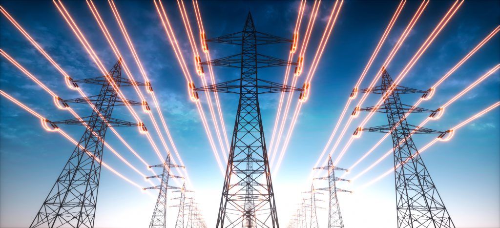 Towering rows of powerlines with glowing wires are photographed on a blue sky backgroup