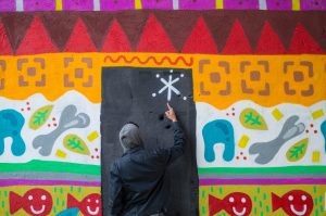 man in hoodie pointing to a star on a graffiti wall