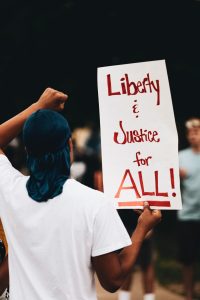 Protestor with a sign saying 'Liberty & Justice for ALL'